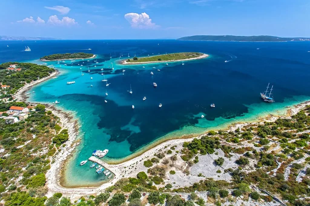 Boats anchored in the shallow turquoise water of the Blue Lagoon at Krknjaši near Trogir, Croatia
