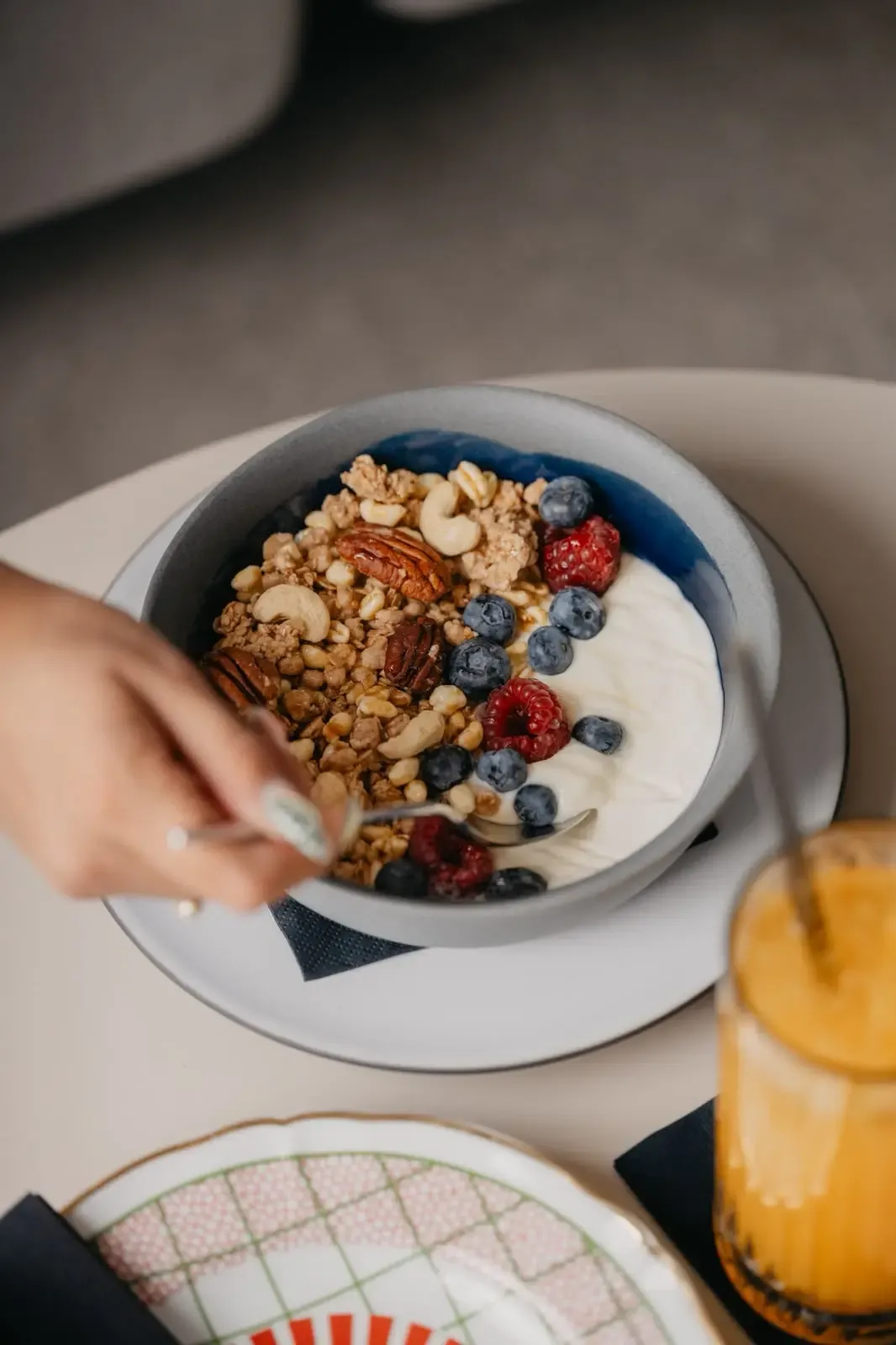 A breakfast bowl of yogurt, granola, nuts and berries with orange juice in Split, Croatia