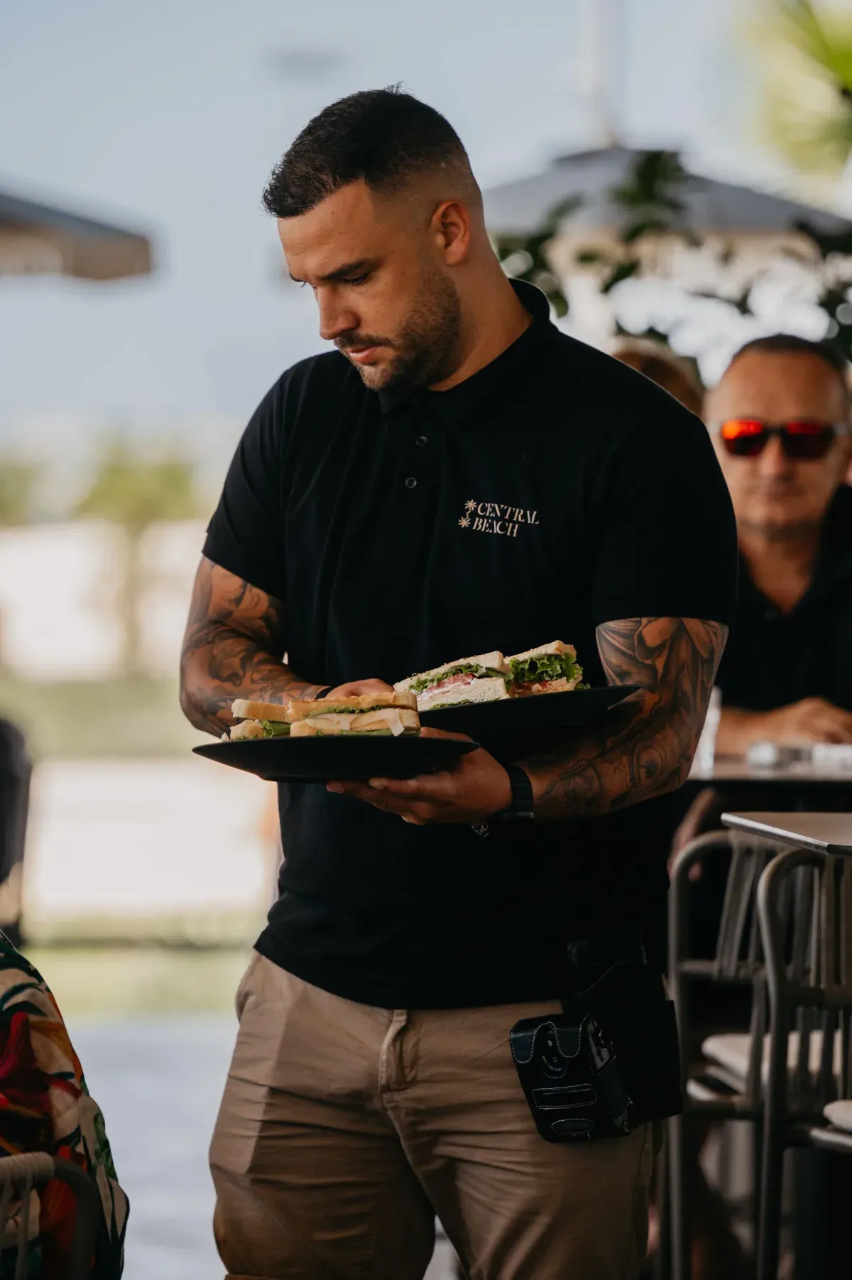 A Central Beach waiter carrying breakfast plates on the terrace at Žnjan beach in Split, Croatia