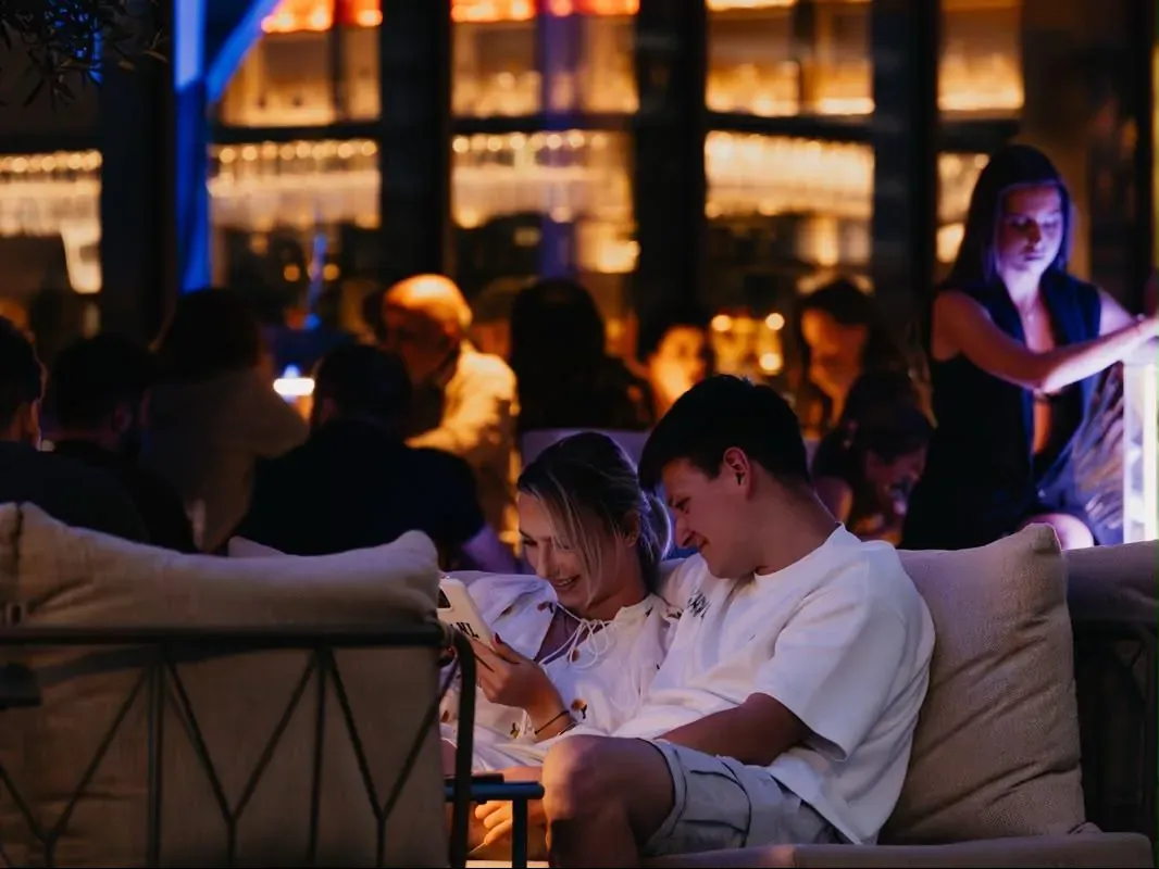 Two guests looking at a menu together on a sofa at Central Beach Split