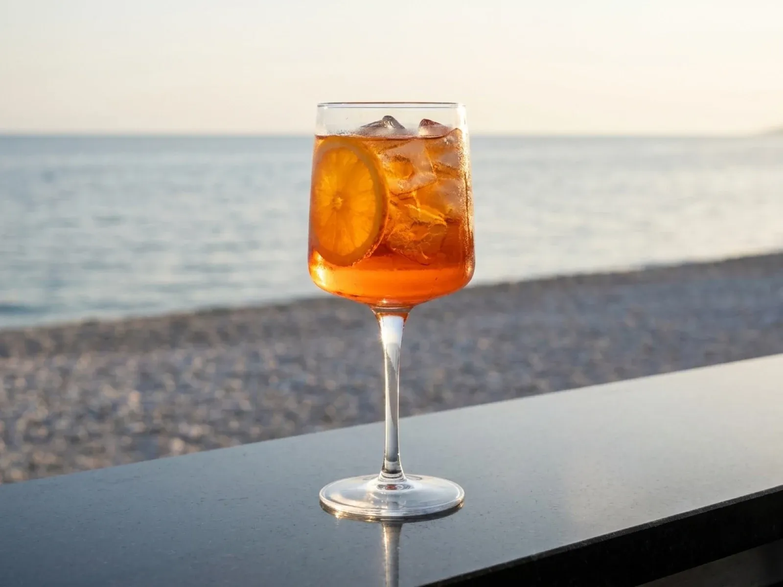 A Martini Fiero spritz with an orange slice, on a bar top above the pebble beach at Znjan, Split