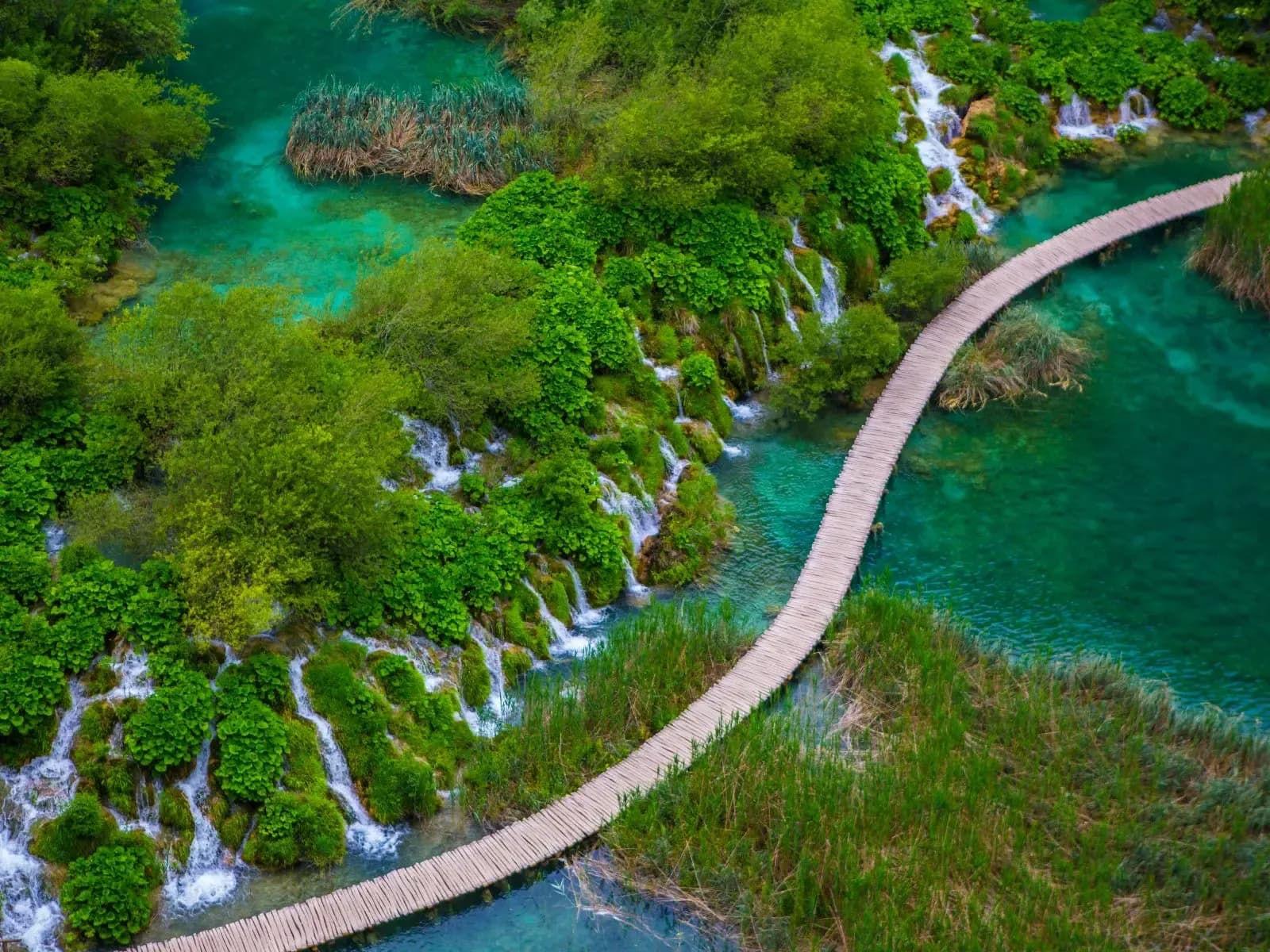 A wooden boardwalk over the turquoise lakes and waterfalls at Plitvice Lakes National Park, Croatia