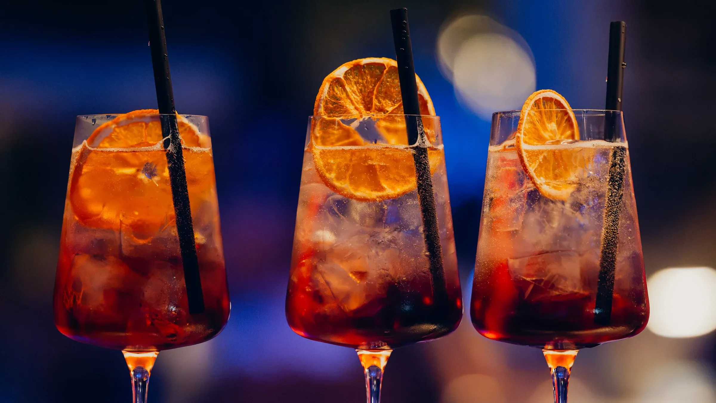 Three orange spritz cocktails with dried orange garnish lined up on the bar at Central Beach Split, Croatia